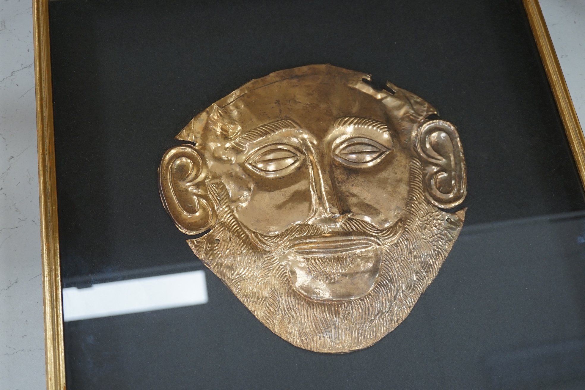 A museum type replica of an Agamemnon mask, copied from the gold mask of the king from the fifth Royal tomb on the Acropolis of Mycenae, 16th century B.C., made in Greece. Condition - good.